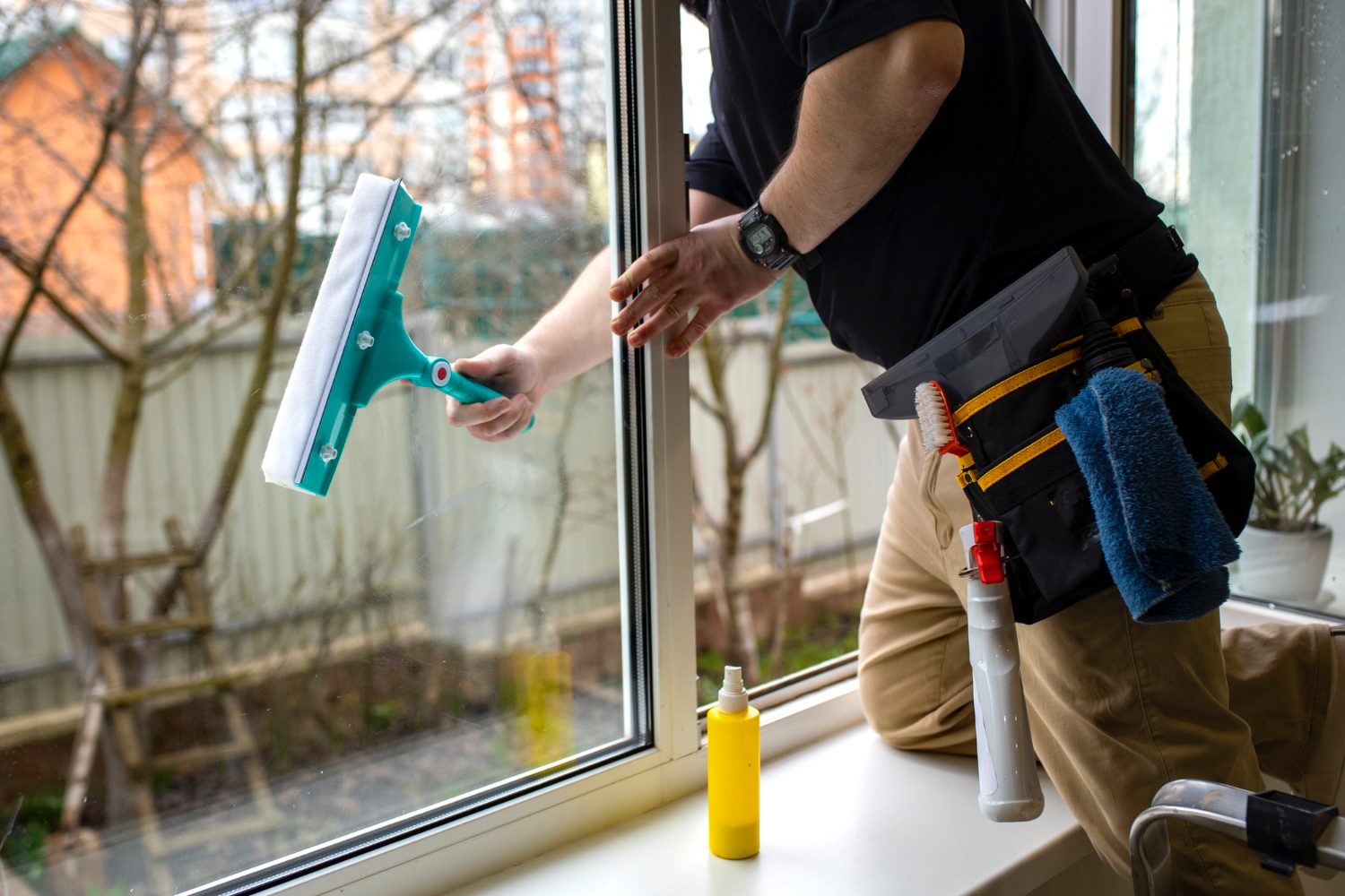 Squeegee cleaning patio doors with sunlight beaming through